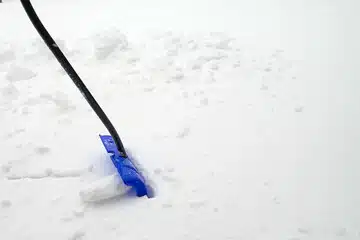 Utilisation d'une pelle en plastique pour déneiger son jardin en gazon synthétique